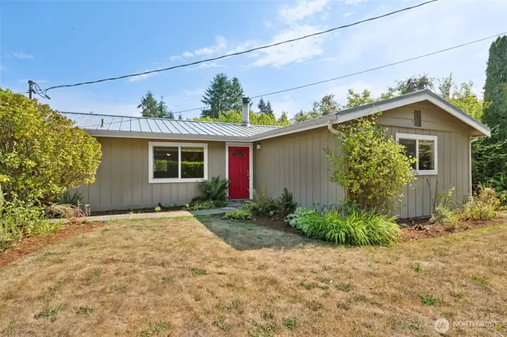 Nothing says welcome like a bold red front door, especially when it’s paired with clean tan siding and white trim. The barked flower beds are loaded with established plantings, which means instant curb appeal, and the walkway up to the house feels like it was designed for a grand entrance, even if you’re just carrying in groceries.