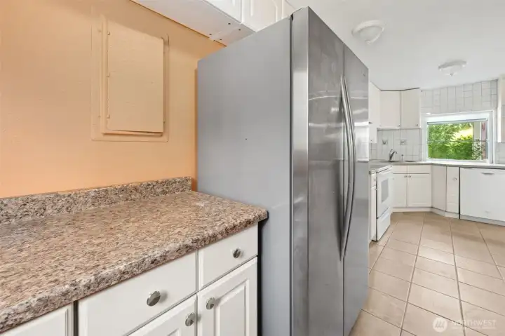 The fridge nook doubles as a pantry zone, with upper and lower cabinets giving you storage you’ll actually use. The electrical panel is neatly tucked here for easy access, and since the fridge stays, you are set up to use the kitchen on day one.