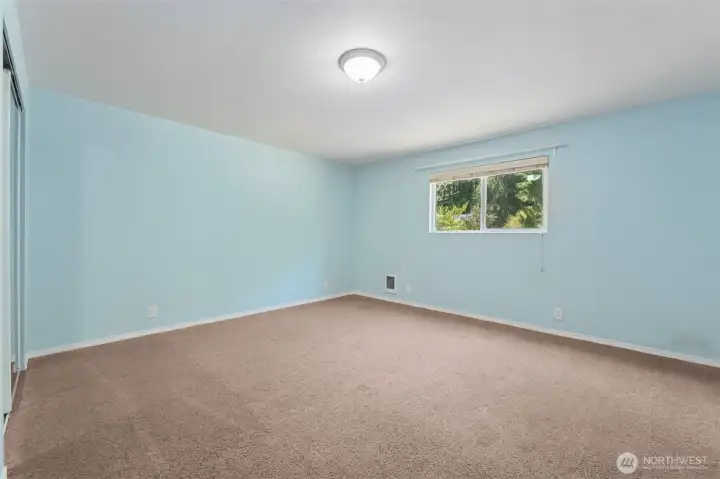 At roughly 15'x15', this bedroom gives you real square footage to work with. Mirrored closet doors double as full-length fit check central or your own dance studio. The barely-there blue walls keep it light, while warm latte carpeting makes the room feel grounded.