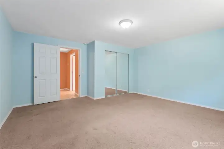 This angle shows just how open the 15 by 15 layout really feels. There’s space here for a full bedroom set without crowding, plus extra room to carve out a reading corner or desk zone. Natural light plays off the soft blue walls, and the mirrored closet doors bounce it back to make the room feel even larger. The latte carpet keeps it grounded and comfortable, so it’s equal parts functional and inviting.