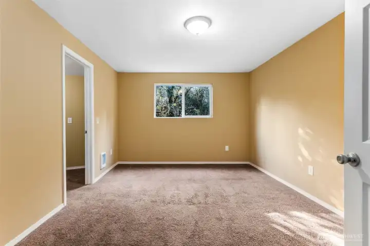 Tan walls give this smaller bedroom some personality, while dark latte carpet grounds it. The walk-in closet is the surprise here, turning the “smallest room” into one that actually pulls its weight. Ideal for a guest space, craft room, or a dedicated Zoom zone.