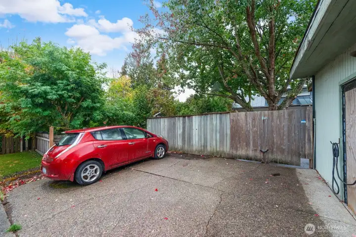 Parking area off alley and EV charger on garage.