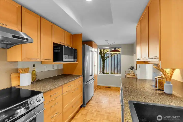 Kitchen with parquet floors, stainless steel appliances, and eating area.