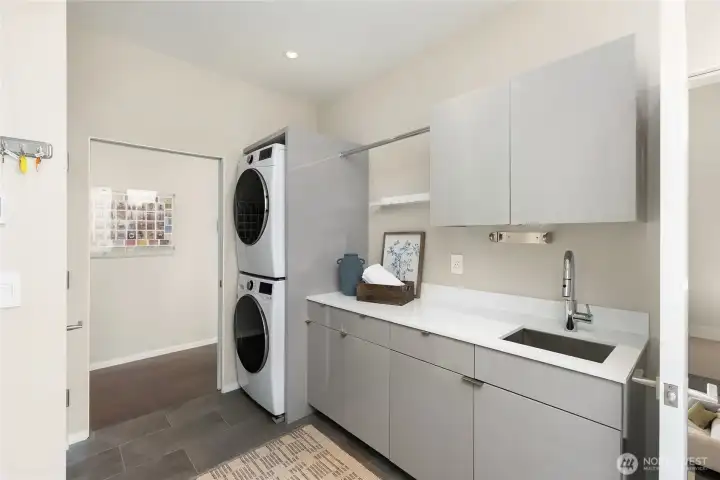 The utility room on the main floor complete with sink, storage and a laundry chute. Steps to the lower level are to the right.