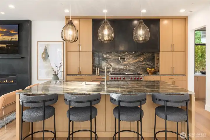 Custom designed and fabricated blackened steel hood accentuated in a full height fireplace surround blackened steel detail. Sleek and contemporary luxury