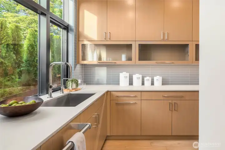 Skullery prep kitchen off the main kitchen includes more custom cabinetry with slab counter prep space, tile backsplash, second Cove dishwasher with rift oak paneling, 30" Wolf Wall Microwave, and 30" Wolf Wall Oven (making this the 3rd prep oven in the kitchen)