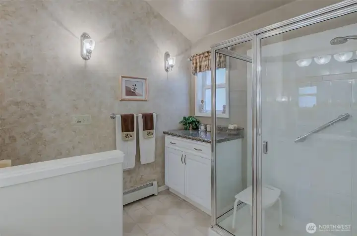 Primary bath has additional vanity area, oversized walk-in shower, and vaulted ceilings