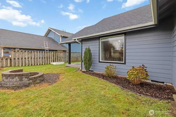 Fenced Front yard boasts a custom firepit.
