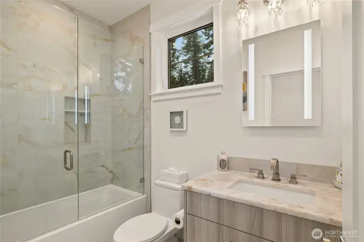 Main level guest bathroom is next to the 2nd bedroom. Quartzite countertop and large-format porcelain shower/tub combo.