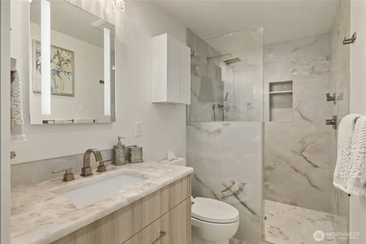 The lower level bathroom with quartzite countertops and large-format porcelain tile is next to the 3rd bedroom.