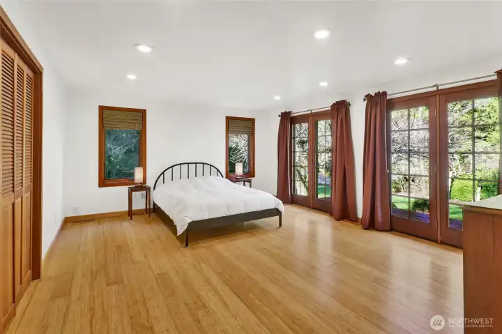 Gorgeous Primary Bedroom with a wall of French doors provide a beautiful back drop of nature and light. Warm bamboo flooring and a wall of closet space.