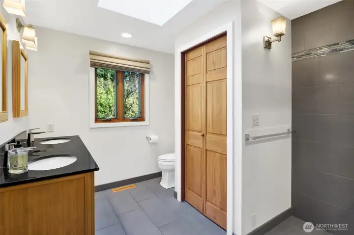 Remodeled Primary Bath with dual vanity and radiant tile floors and tilted shower with glass enclosure.
