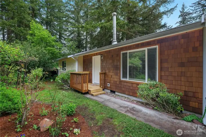 Welcoming front entry with cedar-style accents, fresh paint, and a peaceful wooded setting.