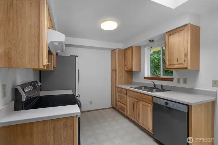 Updated kitchen with wood cabinetry, stainless dishwasher, and generous counter space - All Appliances stay!