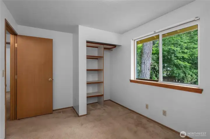 BR 3 - Bedroom with built-in closet shelving and large window overlooking the greenery.
