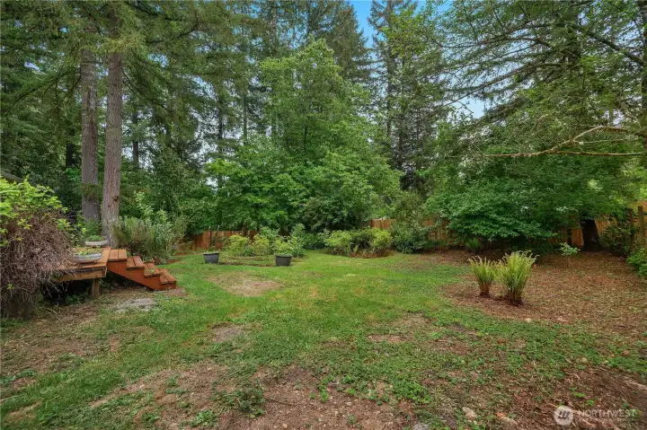 Private backyard setting with mature trees, (organic) garden areas, and room to relax or play.