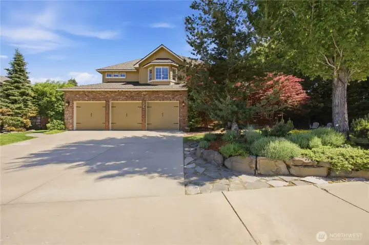 Stunning front exterior of remodeled two-story home with updated curb appeal, triple-car garage, mature landscaping, and spacious driveway in desirable neighborhood.