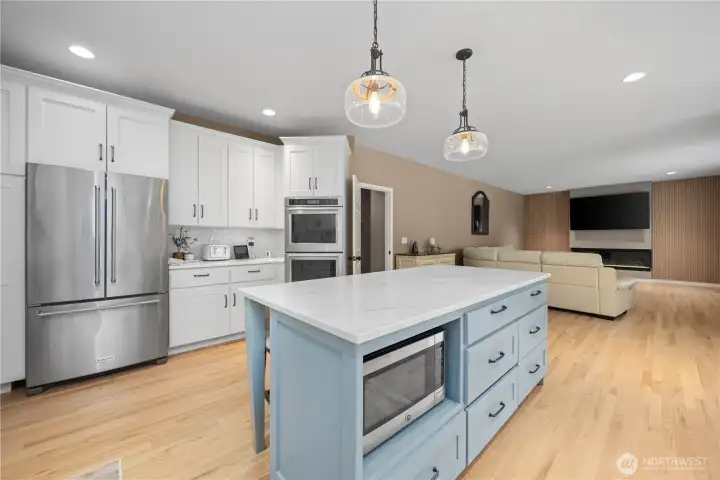 Open kitchen and living room concept with hardwood flooring, tall ceilings, updated fireplace, and ideal entertaining flow.