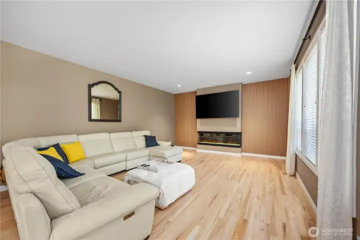 0344 – Inviting family room with modern fireplace feature wall, oversized windows, and seamless flow into the remodeled kitchen and dining spaces.