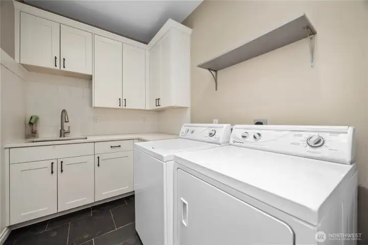 Functional laundry room with extensive storage cabinetry, workspace potential, and convenient main-level access.