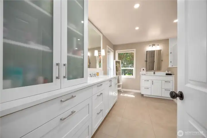 Luxurious primary bathroom with split vanities, updated counters, tile flooring, and spa-inspired design.
