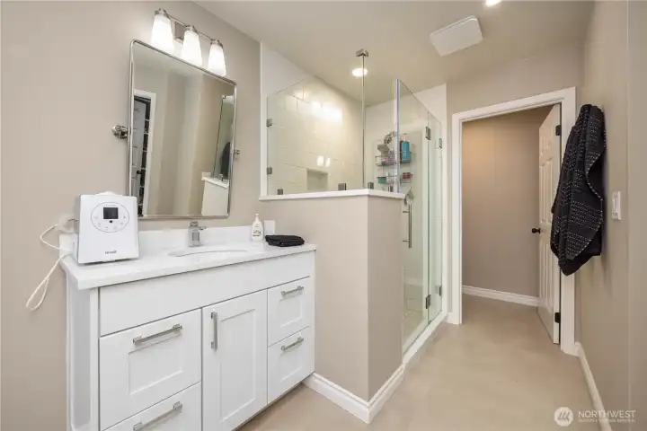 Primary bath featuring double vanities, updated lighting, tile finishes, and modern functionality.