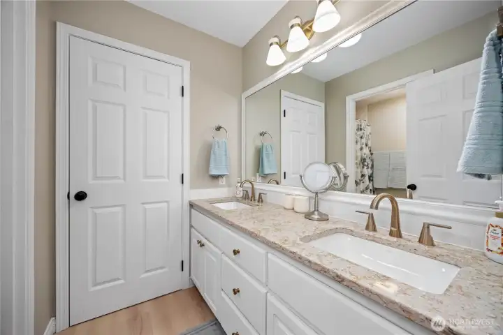 Updated main bathroom with granite double sinks, tiled shower surround, and modern finishes.