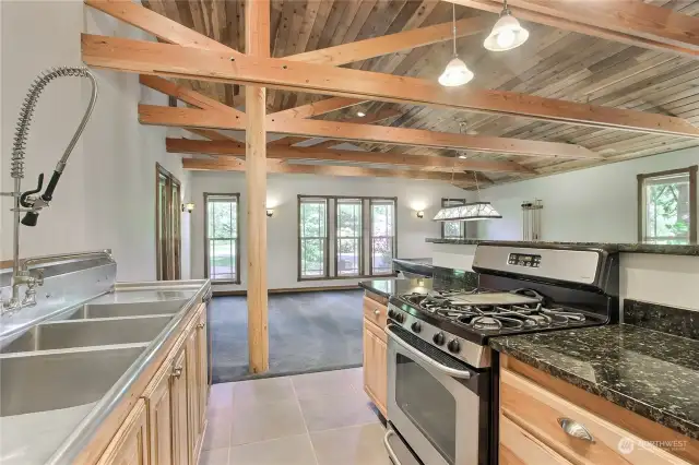 This view is your SECOND kitchen with stove/range, mini fridge and large stainless commercial sink. Straight ahead is your family room with included pool table, love all the windows and again with the beams!