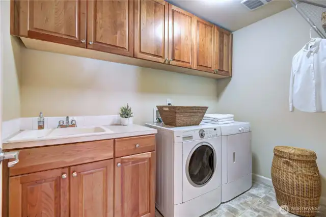 Upper laundry room with full capacity of washer and dryer, many cabinetries, utility sink.