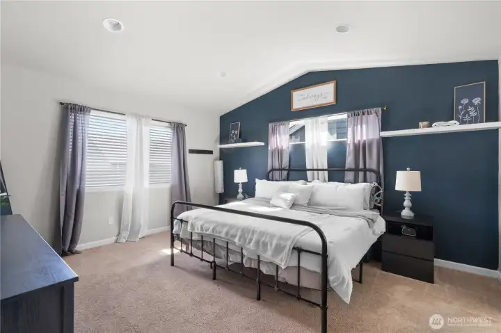 A gorgeous primary retreat featuring dramatic vaulted ceilings and bathed in tons of natural light