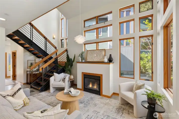 The living room from the window side — the cathedral ceiling, open staircase, and layered natural light make this feel far removed from a typical townhome.