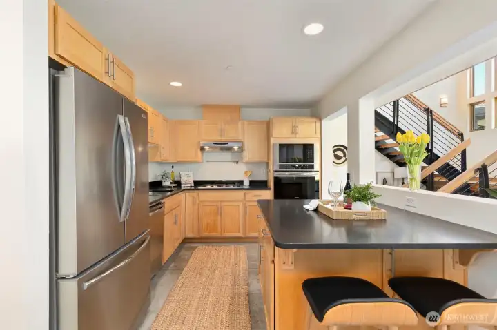 The dining area with bar seating at the island beyond — a comfortable everyday space with access to the garden patio just out of frame.