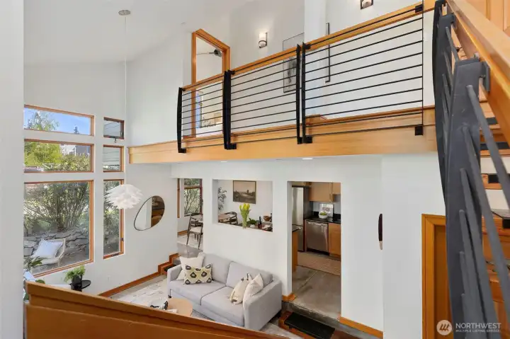 View from the staircase landing — the open railing gives the upper level a connection to the living space below and the garden beyond.