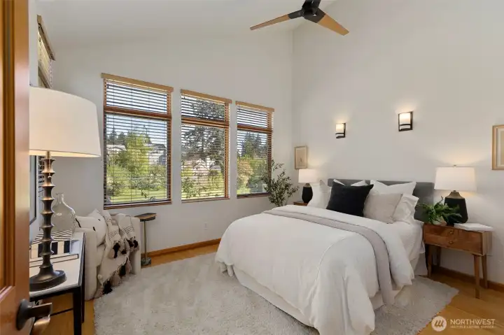The primary bedroom with vaulted ceiling, ceiling fan, multiple windows, and a calm, well-proportioned layout.