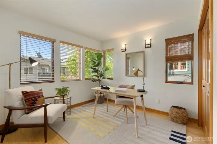 The third bedroom is staged as a home office — corner windows, bamboo floors, and enough room to function well in either configuration.