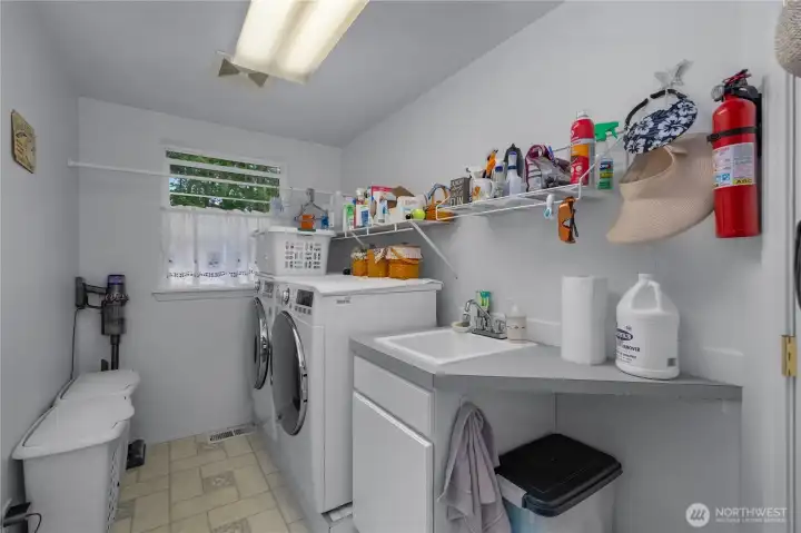 Utility room with elevated washer and dryer, utility sink, counter, storage area too.