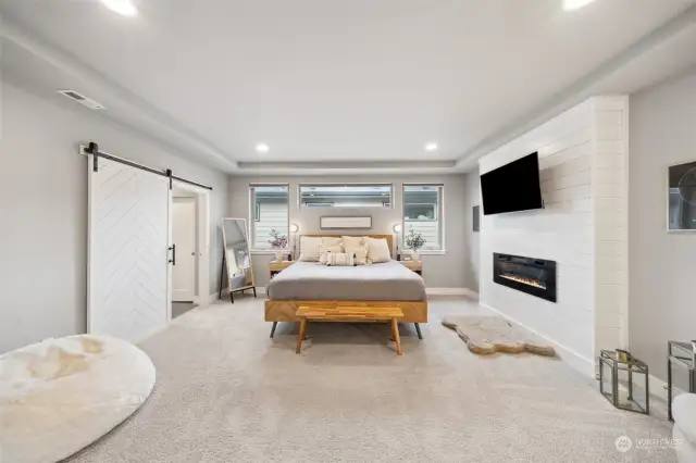 Primary suite with electric fireplace and barn door to bathroom.