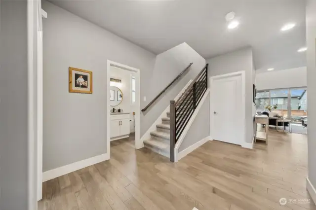 Wide open entry way with 5th bedroom to the left and powder room to the right of it.