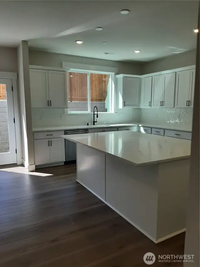 Bright kitchen featuring quartz counters, GE cafe gas range, dishwasher and microwave.