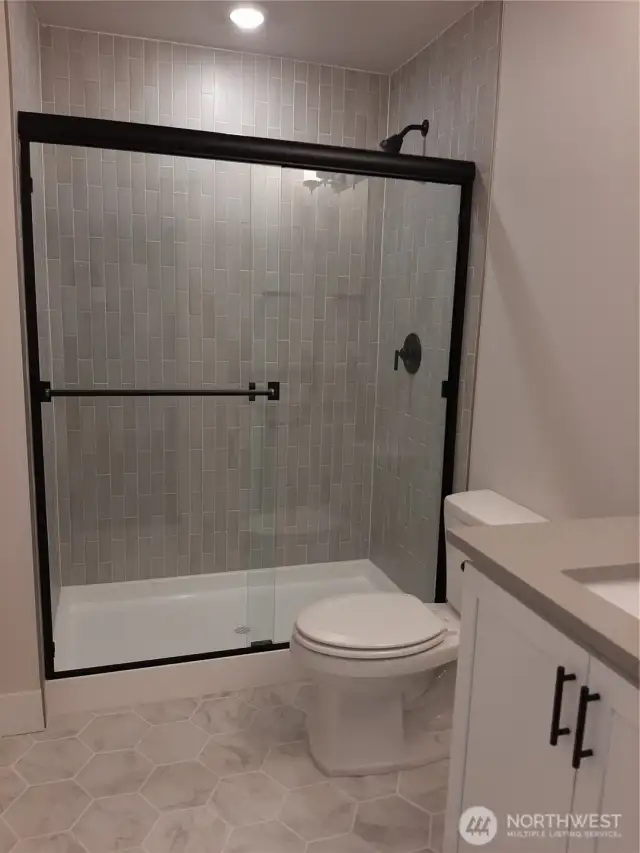 Lower level bath highlights upgraded matte black hardware throughout the home.