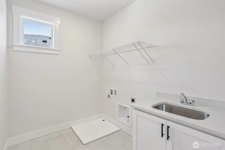 Convenient 2nd floor laundry room highlighted by a utility sink and storage cabinet.