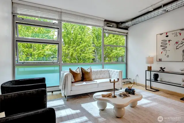Floor-to-ceiling steel windows frame lush, park-like setting
