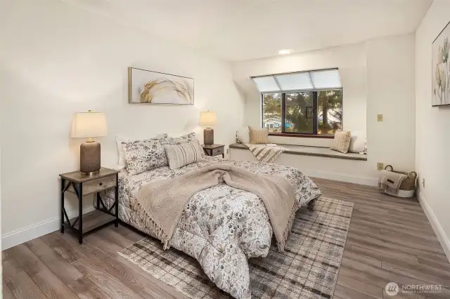 Spacious bedroom with solarium style window and bench seating.