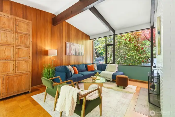 Rich mahogany paneling wraps the end wall of the sitting area, anchored by a classic wood-burning fireplace.