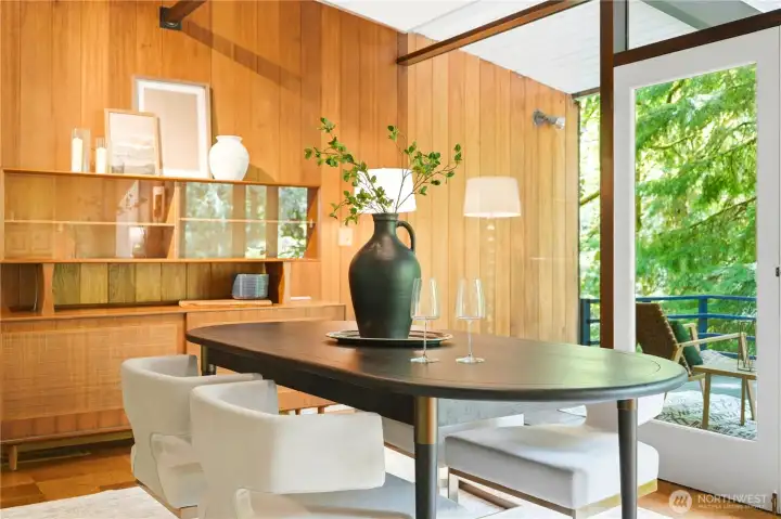 Mahogany paneling carries into the dining area, with French doors opening to the forest view deck beyond.