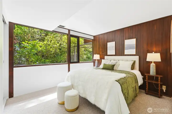The lower-level primary suite with the mahogany paneling and tranquil views of the surrounding landscape.