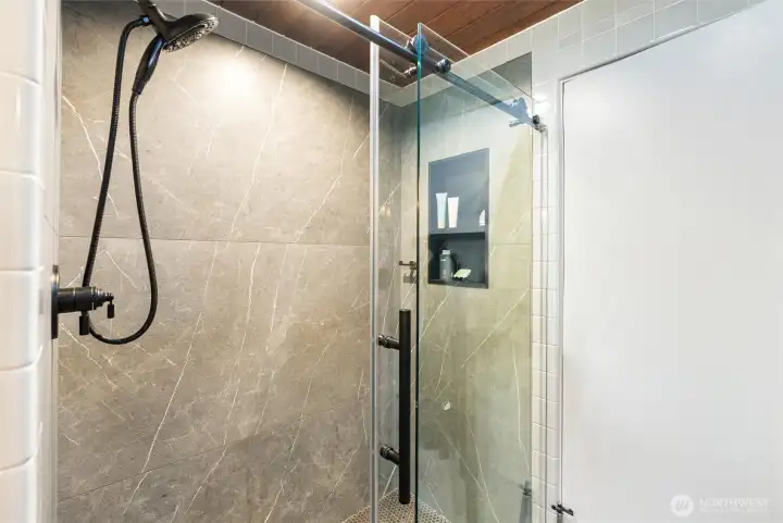 Oversized walk-in shower with sleek tilework and contemporary black fixtures for a clean, modern aesthetic. Oversized walk-in shower with sleek tilework and contemporary black fixtures for a clean, modern aesthetic.