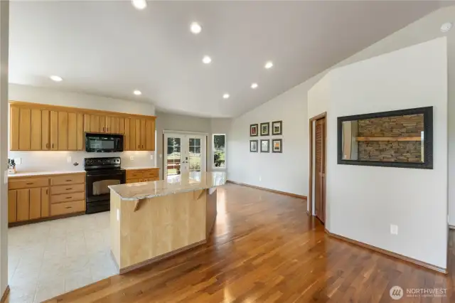 Stunning granite counters. Island with informal seating. Stay connected with guests at all times in this open concept floor plan. French doors open to the covered deck and outdoor seating.