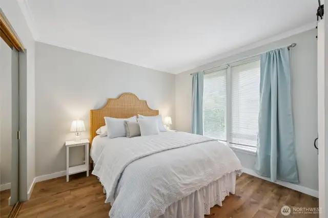 Primary bedroom with an en-suite bathroom. Warm wood floors.