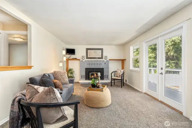 Main Level Living room open to the Kitchen and East Deck.  Cozy fireplace with a great wood supply from your own acreage.